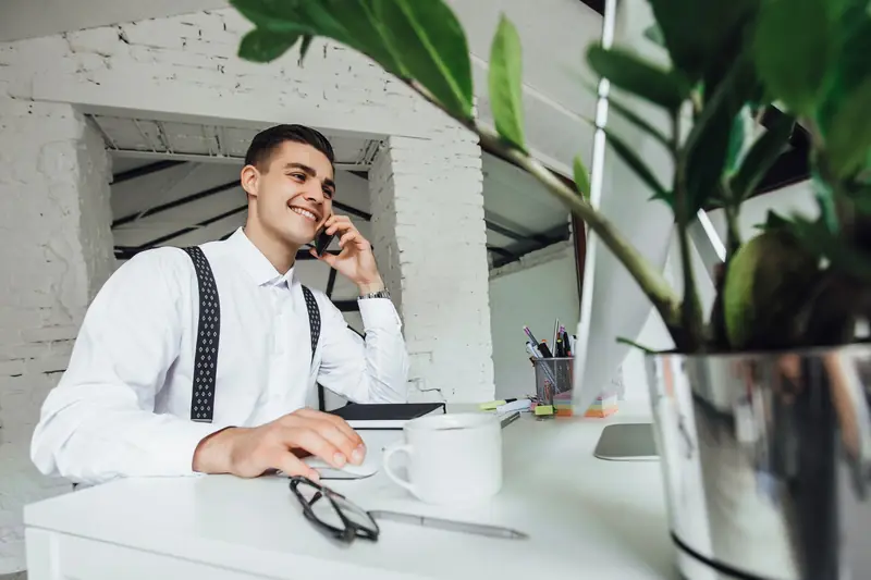 Dirigeant souriant au téléphone à son bureau